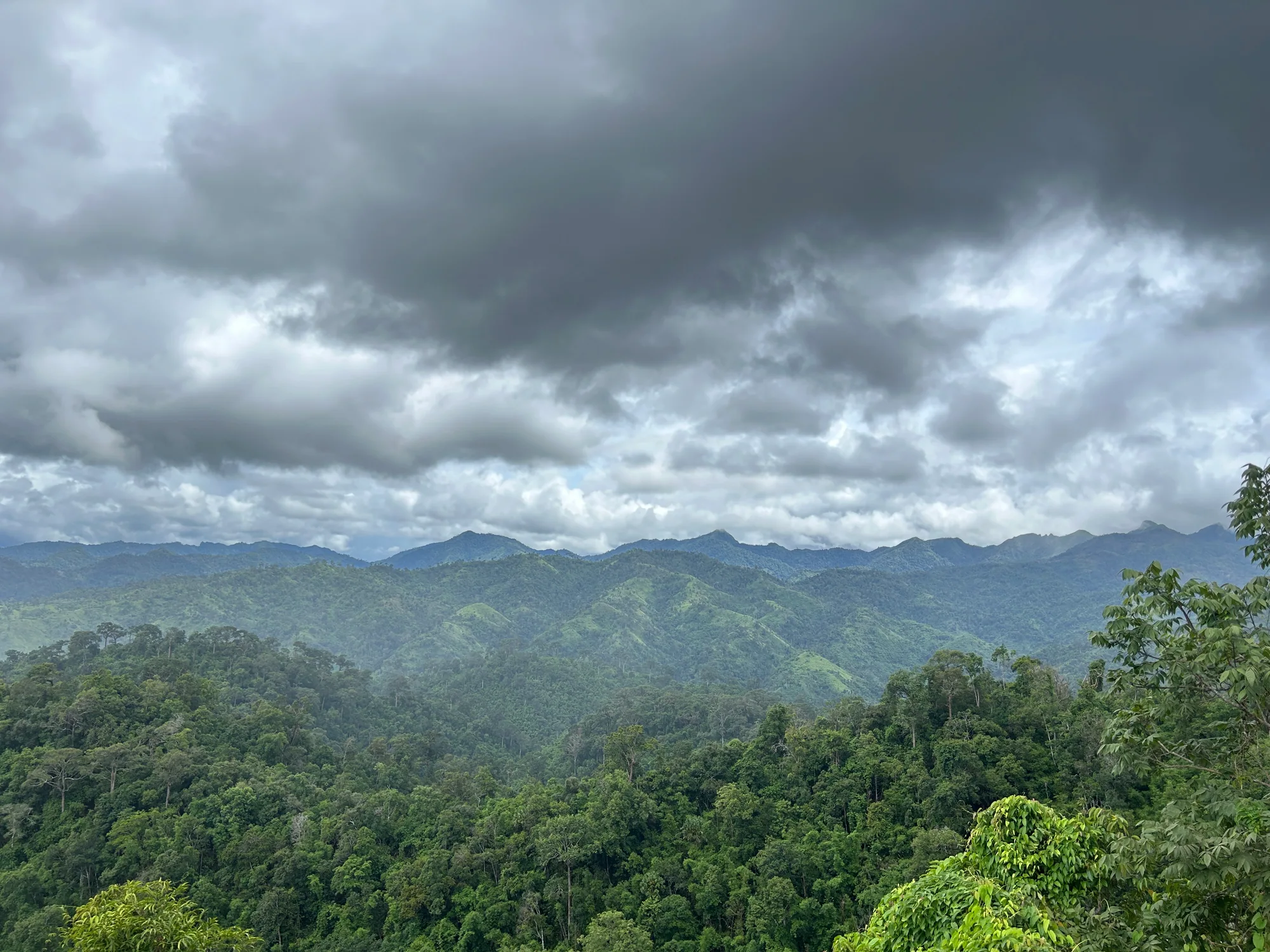Layers of green forested mountains beneath a dramatic cloud-filled sky